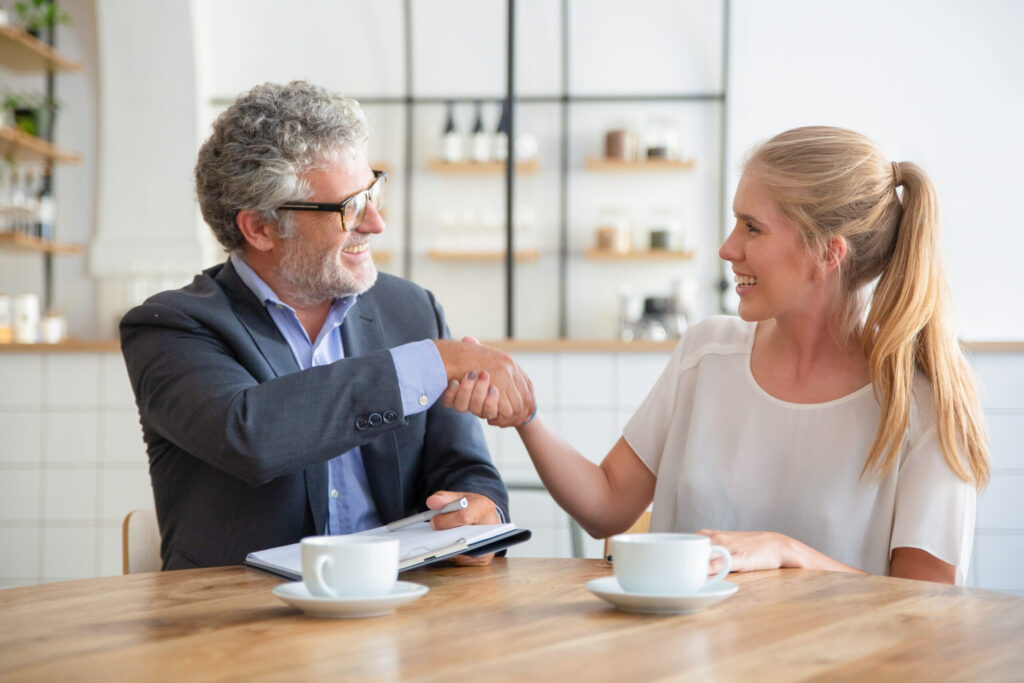 Insurance agent shaking hands with a client across a table
