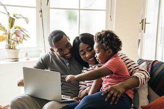 Parents and child looking at a laptop together at home